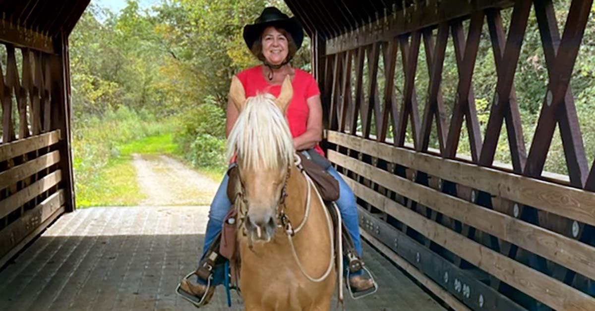 AFib implant patient rides her horse over a bridge.