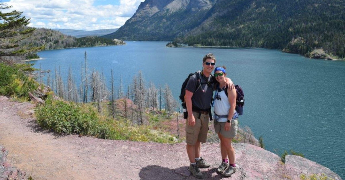 Caline Long, a physician assistant with BayCare Clinic's emergency medicine department, poses with her husband in front of a lake and mountain scene.