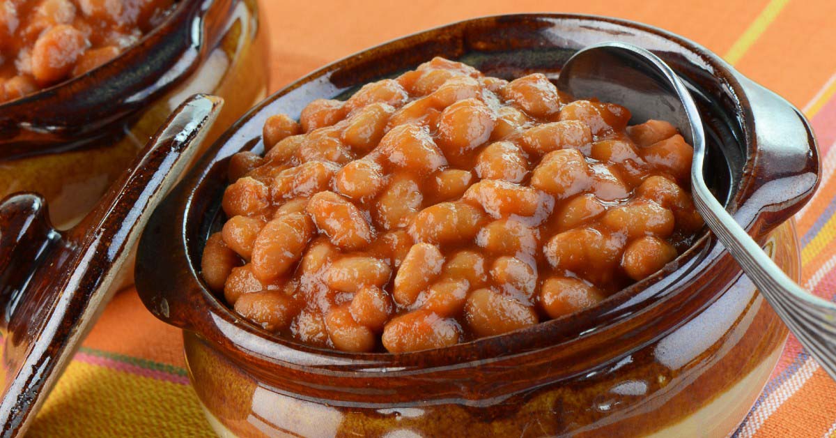 A small bowl of baked beans with a spoon.